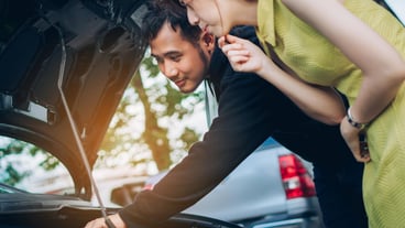Young man with woman repairing car engine