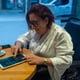 Woman in Wheelchair Interacting with Tablet Over Coffee