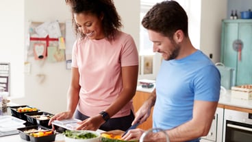 Couple Preparing Batch Of Healthy Meals At Home In Kitchen Together