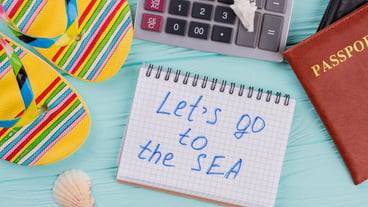 Travel planning concept at office with passports, sandals and calculator. Let's go to the sea written on notepad.