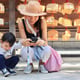 Woman using mobile phone by boy while crouching on footpath