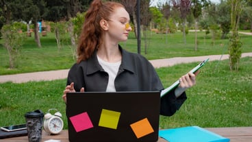 Girl with red hair working at laptop holding folder