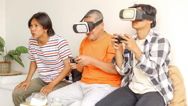행복한 아시아인 아버지와 아들이 VR 안경을 착용하고 함께 비디오 게임을 하고 있습니다.