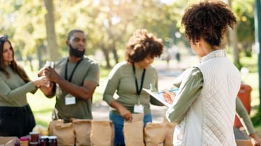 Woman clipboard and volunteering group or helping kindness ngo and charity project with community in park Distribution food parcel and grocery boxes for donation teamwork and care with checklist