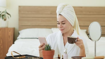 Portrait of a positive young woman drinking coffee after her morning shower and checking social media