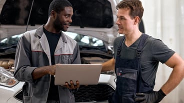 Computer car tuning two smiling auto mechanic testing a car engine connected to laptop in auto repai