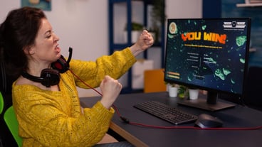 Excited happy competitive winner woman gamer winning space shooter videogames during online championship celebrating game at home in living room. Player playing on RGB powerful computer