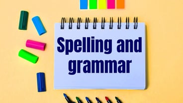 On a beige wall, a notebook with the words SPELLING AND GRAMMAR, bright felt-tip pens and stickers