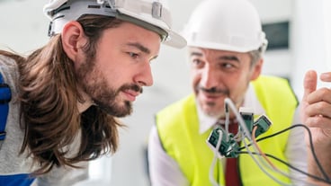Un elettricista sta montando delle prese elettriche sulla parete bianca interna.