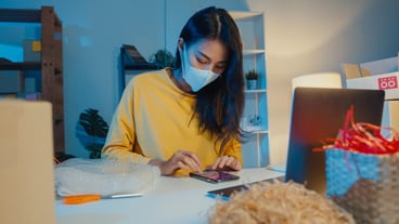 Young asian businesswoman wearing face mask checking purchase order on smartphone