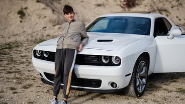 Teenager boy stand near white muscle car Young teen driver