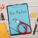 Medecine and diet concept clipboard with text Go Paleo pills fruits stethoscope book eyeglasses