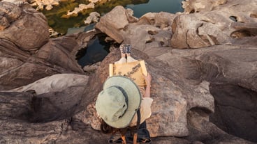 Explorer asian woman sitting on rock cliff with looking at paper map in Sam Phan Bok grand canyon of Thailand