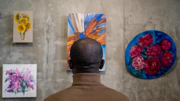 Rear view of young african man looking at paintings on wall