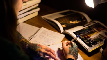 High angle view of a woman writing a book at a table.