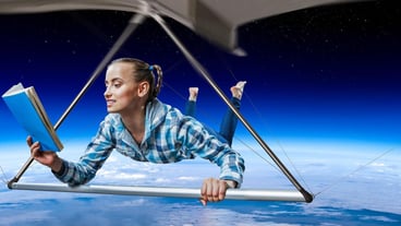 Young joyful woman flying on hang glider. Mixed media
