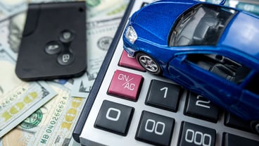 Blue toy car with real keys calculator over us dollar banknotes