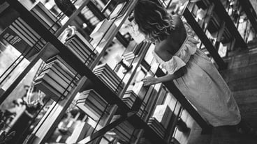 High angle view of woman standing at bookshelf in library