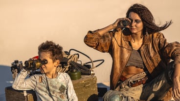 Post apocalyptic hero woman and boy with binoculars outdoors. Desert and dead wasteland on the
