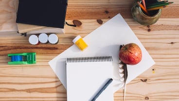 Apple and feather near drawing supplies