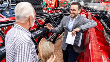 Salesman and farmer discussing about farming equipment and purchase of agricultural machinery