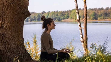 Side view of young woman meditating by lake