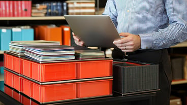 Man working with a laptop and organizing paperwork in an office environment