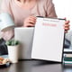 Woman hands holding resume application near her workplace with laptop.