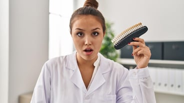 Young hispanic dentist woman holding teeth whitening samples scared and amazed with open mouth for surprise, disbelief face