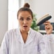Young hispanic dentist woman holding teeth whitening samples scared and amazed with open mouth for surprise, disbelief face