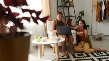 Lesbian couple eating nachos and watching movie online on laptop in living room