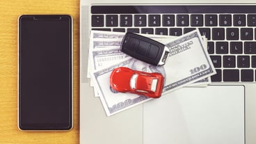 Smartphone near Car model, money and Notebook on wooden desk. shopping online and car payment by using laptop