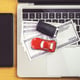 Smartphone near Car model, money and Notebook on wooden desk. shopping online and car payment by using laptop