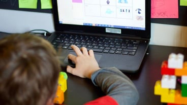 Rear view of child using laptop on table
