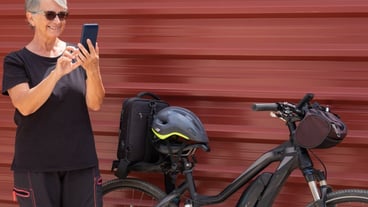 Smiling elderly cyclist on urban city tour with mobile phone enjoying healthy lifestyle