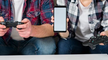Mid section of young couple playing video game showing smart phone with blank display screen