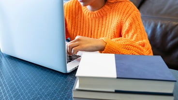 Woman with computer and books at home working