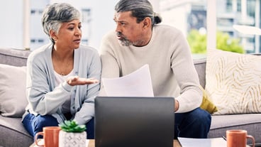 Senior couple documents and stress on laptop with financial paperwork taxes or retirement questions at home Planning debt and elderly people on sofa for life insurance bills or asset management