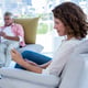 Woman using phone while man reading newspaper