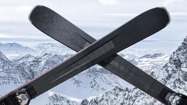 Pair of cross skis. closure of ski resort or ski season. Black alpine skis are crossed. snow mountains in background. close of ski resorts, end of season, lockdown