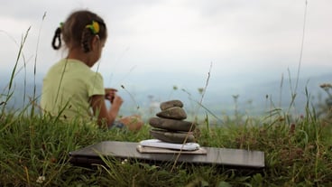 Cute girl relaxes in the mountains stack of zen stones and digital gadget laptop and mobile phones