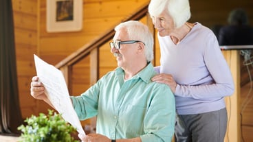 Happy mature man and his wife reading latest news in newspaper in the morning after breakfast