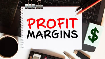 Red pen and notepad with text PROFIT MARGIN in the white background