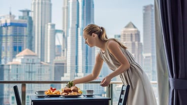 Young woman is laying on a table Breakfast table with coffee fruit and bread croisant on a balcony against the backdrop of the big city