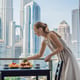 Young woman is laying on a table Breakfast table with coffee fruit and bread croisant on a balcony against the backdrop of the big city