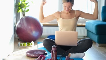 Young happy woman repeats physical exercises look at laptop