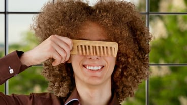 man in a brown shirt uses a wooden comb
