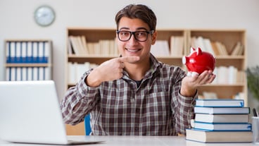 Young student breaking piggy bank to buy textbooks