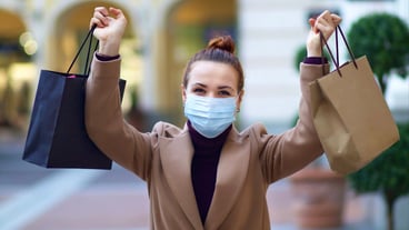Young beautiful happy stylish woman is shopping in the mall, wearing protective medical mask on her