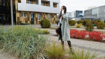 Young stylish business woman talking on mobile phone outside the office